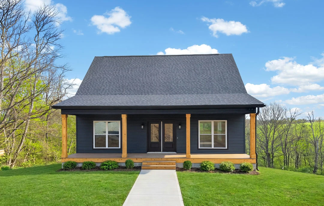 Two-story farmhouse with white siding, a covered porch, double glass entry doors, and a concrete walkway bordered by green grass.