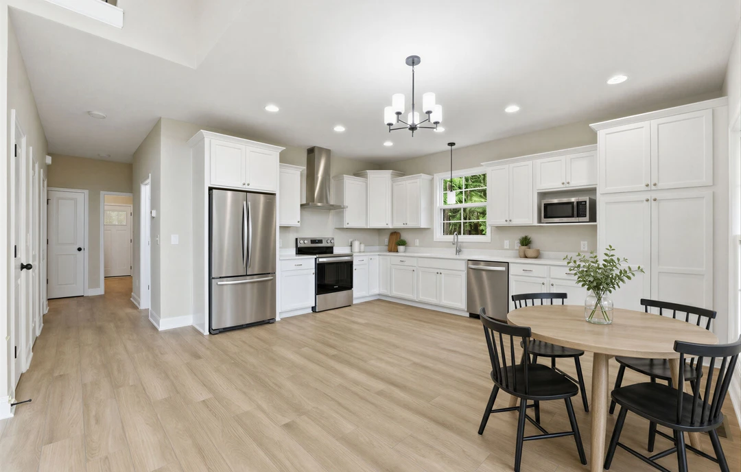 Kitchen with wood flooring, white cabinetry, granite countertops, a dining table surrounded by chairs, stainless steel refrigerator, stove, and a vase with green leaves as a
