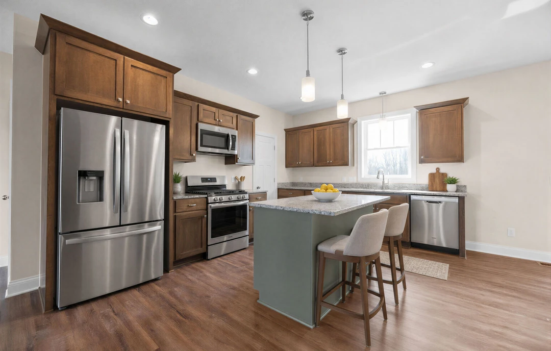 Kitchen with stainless steel refrigerator, built-in microwave above a stove, white cabinetry, granite island countertop with a bowl of lemons, and a bar area with seating.