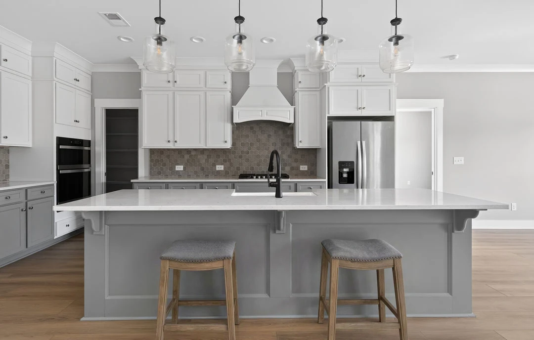 Modern kitchen with white cabinetry, granite countertops, stainless steel appliances, a bar area with cushioned stools, and pendant lighting hanging above.
