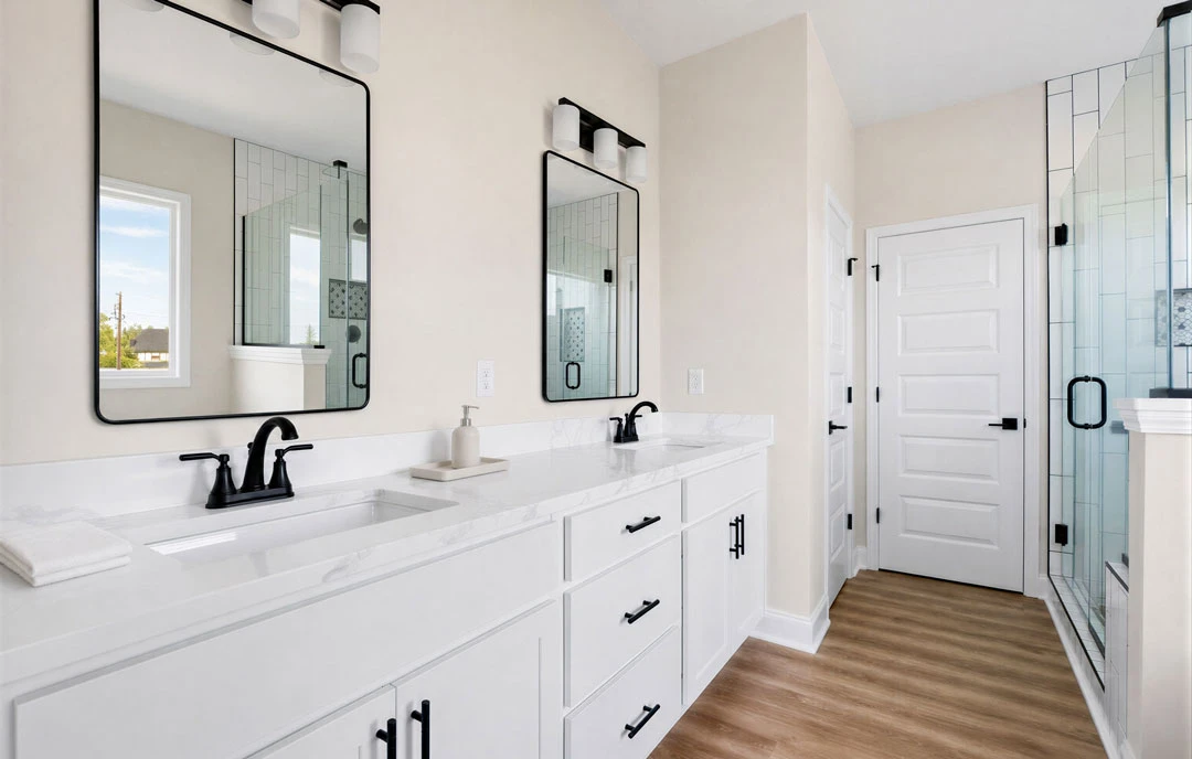 Bathroom with white cabinets and white countertops, a black faucet, wood flooring with white trim, a glass shower door with black frame, and a white door with black handle.