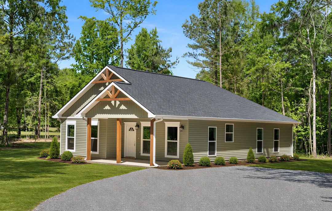 Two-story farmhouse with light siding, a covered front porch, white door, and multiple windows, set behind a driveway bordered by bushes, flowers, and a grassy lawn with mature