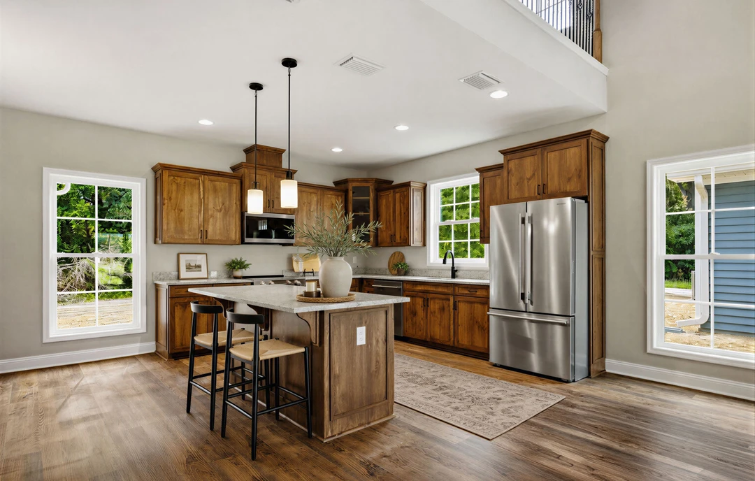 Kitchen with stainless steel refrigerator, wood cabinets, granite countertops, and a kitchen island with stools and a bowl of candles; laminate wood flooring and a window with a