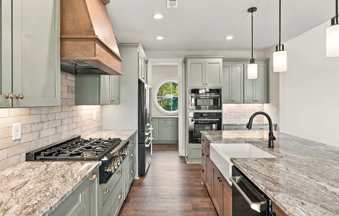 Kitchen with a large central island featuring granite countertops, white cabinetry, stainless steel appliances including a gas stove, oven, microwave, and refrigerator, a black