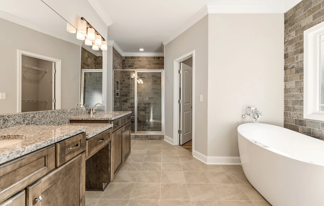 Bathroom with a white bathtub, glass-enclosed shower, white cabinetry, granite countertop, and tile flooring.