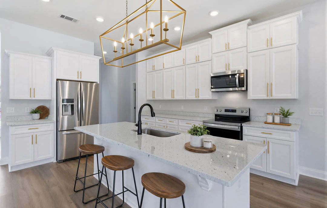 Kitchen with white cabinets, a large granite island featuring a sink and stools, stainless steel refrigerator with ice and water dispenser, built-in microwave, and a stove and oven