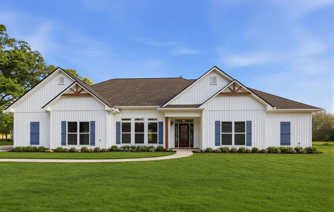 White farmhouse-style home with brown roof, blue shutters, and multiple windows, set on a grassy lawn with a walkway leading to the front door.