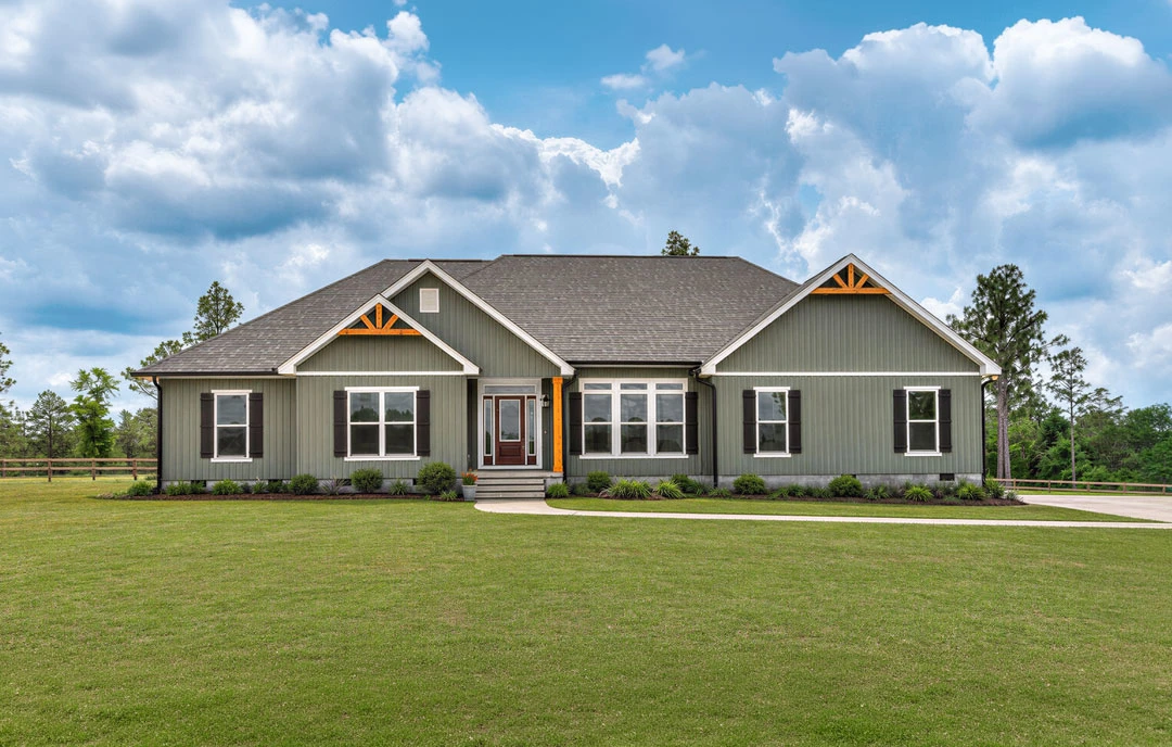 Two-story house with white siding, multiple windows, and a front door, set on a green lawn with a concrete walkway under a blue sky with scattered clouds.