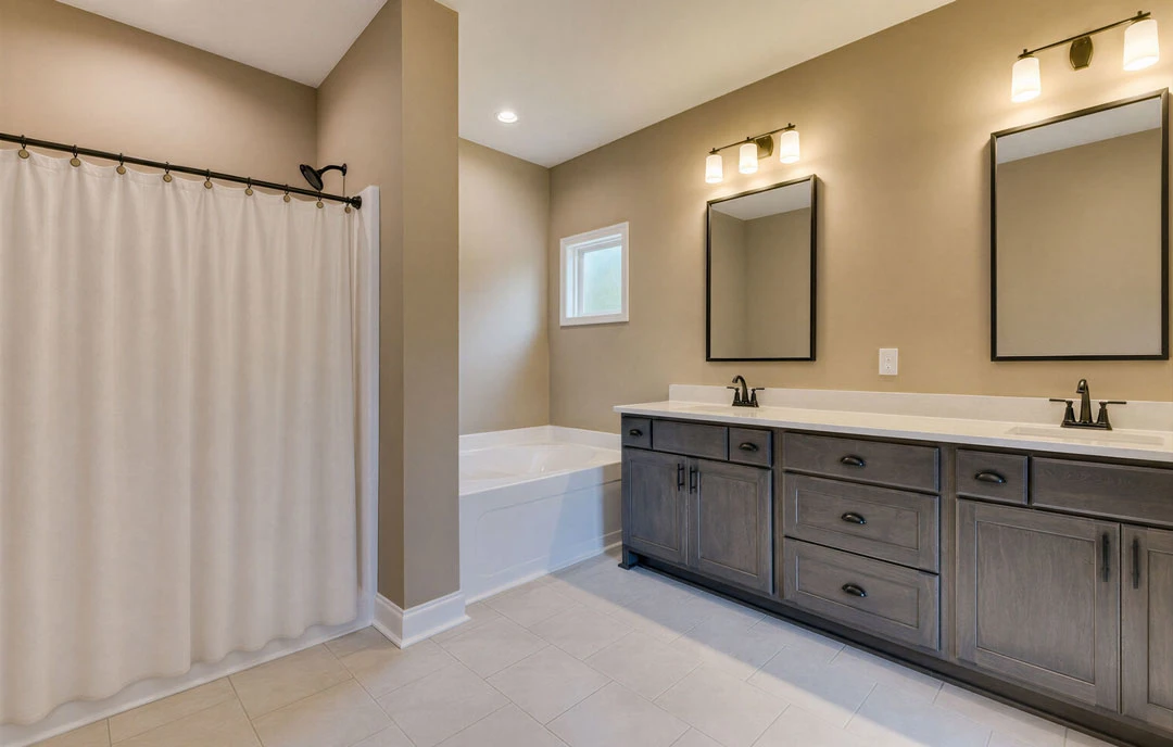Bathroom with a white bathtub and shower curtain, featuring a wall-mounted mirror, white window frame, tile flooring, and a bathroom counter with cabinetry and drawers.