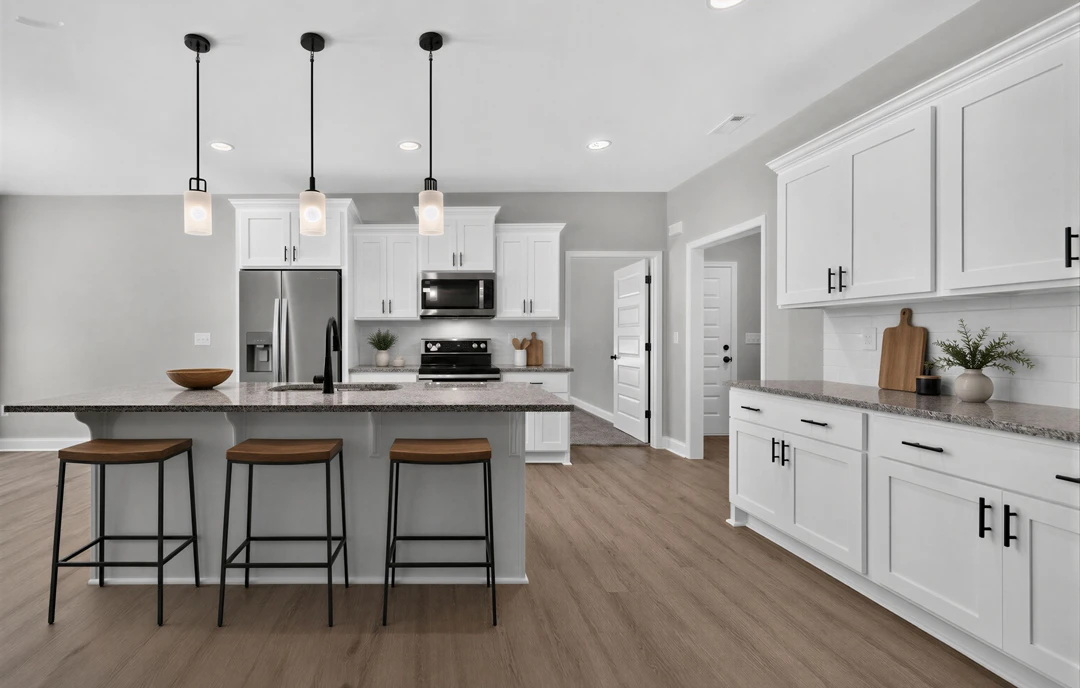 Kitchen with white cabinets, granite countertops, stainless steel appliances including a microwave and refrigerator, wood flooring, black bar stools with wooden seats, and a plant