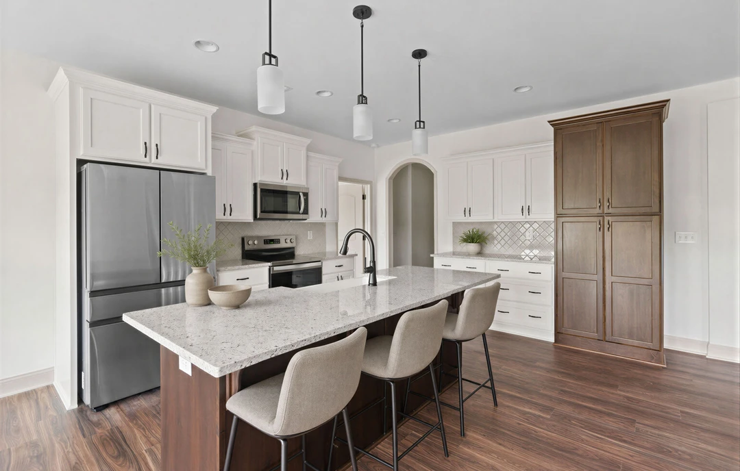 Kitchen with light wood cabinetry, a large granite island with chairs, stainless steel appliances including a microwave, and a bowl on the island countertop.