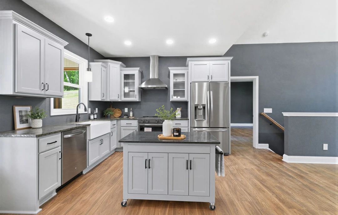 Kitchen with a large island featuring a black granite countertop, stainless steel appliances including refrigerator and vent hood, white cabinetry, and potted plants on the