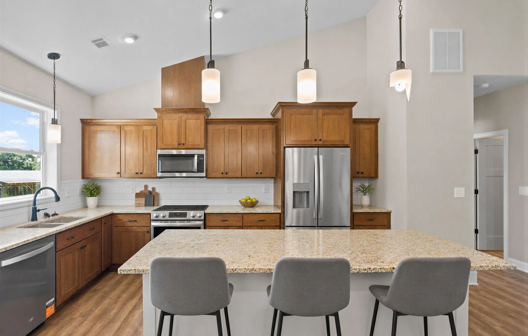 Kitchen with granite countertops, stainless steel refrigerator, white cabinetry, and a stove, with a chair positioned at the counter.