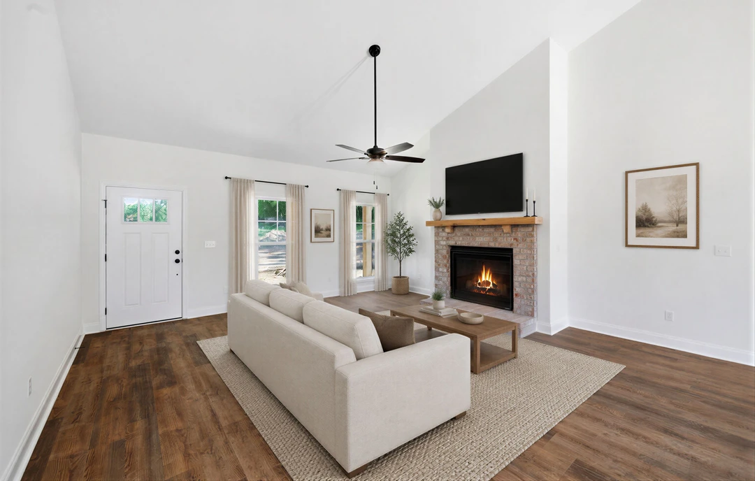Living room with a gray couch facing a fireplace with a fire burning, wood or laminate flooring, a ceiling fan with light, a framed tree picture on the wall, and a white door with