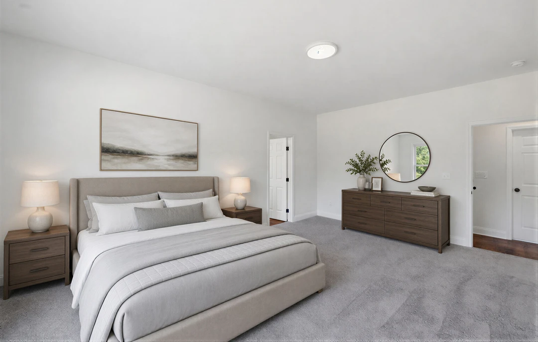 Bedroom with a large bed featuring white bedding, a landscape painting above the headboard, a dresser topped with a white bowl, and a white lamp with a matching shade next to a