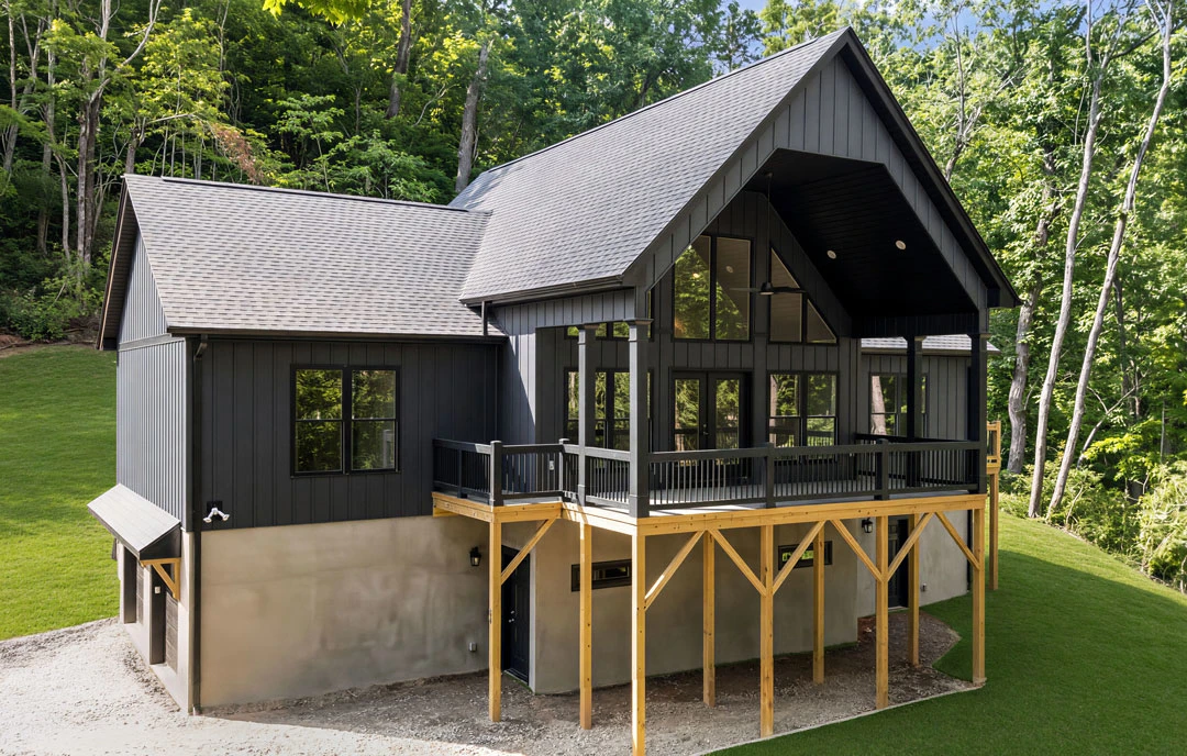 Two-story house with a wooden deck featuring railing, surrounded by a green lawn and mature trees in the background.
