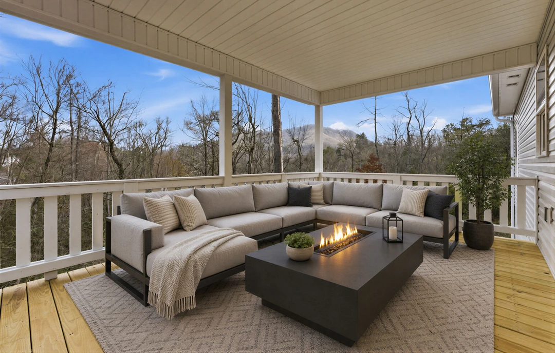 Outdoor deck with a cushioned couch and a fire pit, potted plants nearby and a pillow on the seating.