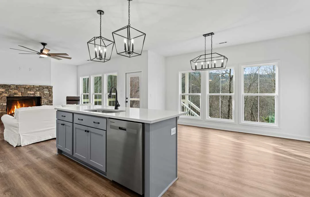 Kitchen with a large central island featuring granite countertops, white cabinetry, stainless steel appliances, laminate flooring, and multiple windows allowing natural light.