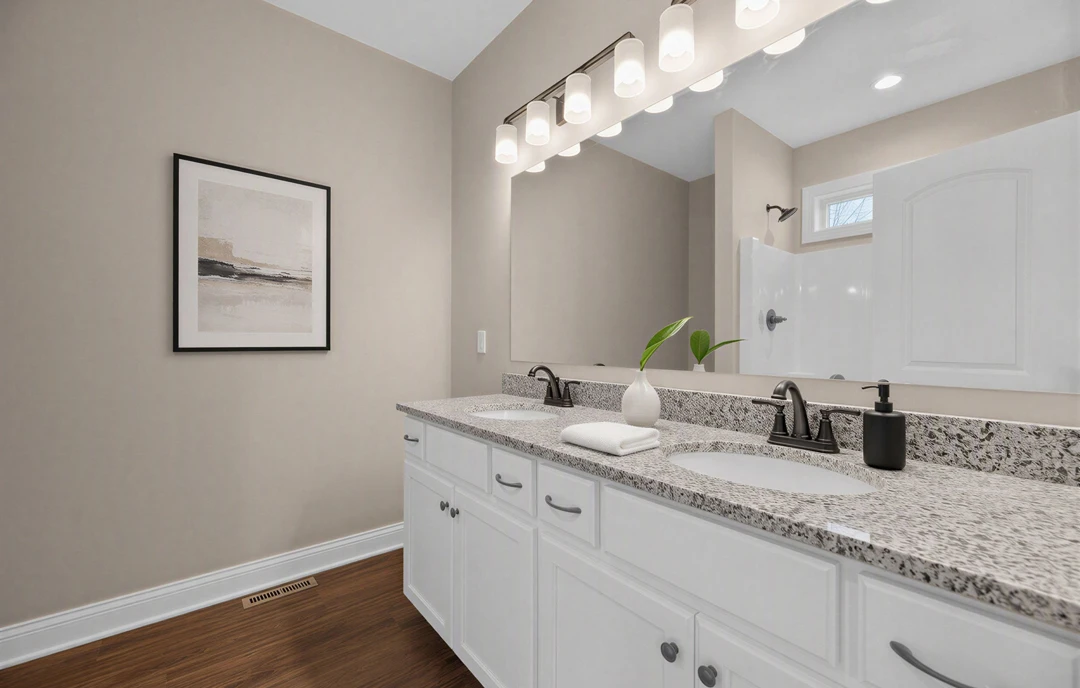 Bathroom with a white granite countertop vanity, rectangular mirror above the sink, wood flooring with a floor vent, and a black soap dispenser next to a framed wall art.