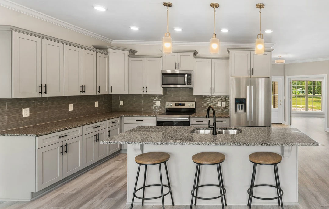 Kitchen with granite countertops, stainless steel refrigerator, white cabinetry, built-in microwave, and wooden seat stools along the island.