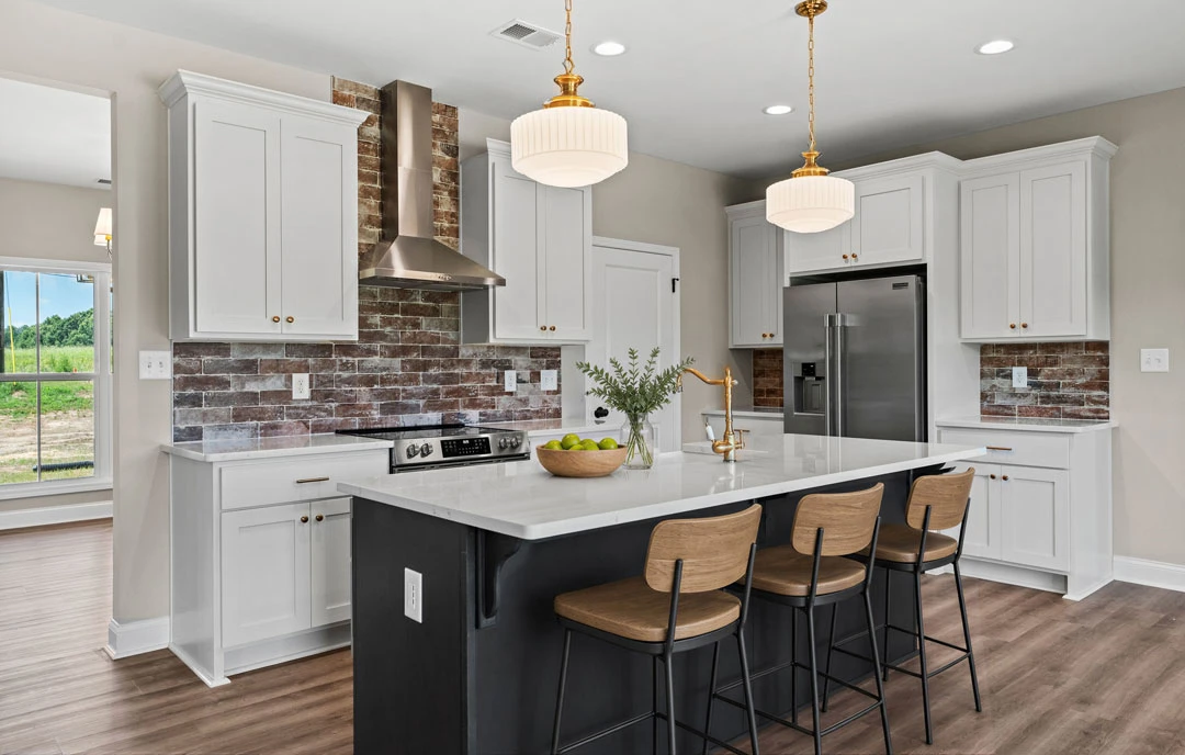 Kitchen with a central island featuring granite countertops, wooden cabinetry, stainless steel refrigerator, stools at the island, a bowl of fruit on the counter, and a window