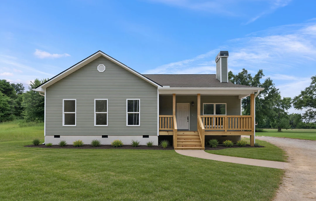 Two-story house with white siding, a covered front porch, white-framed windows, a white door with a black handle, and a green lawn bordered by trees.
