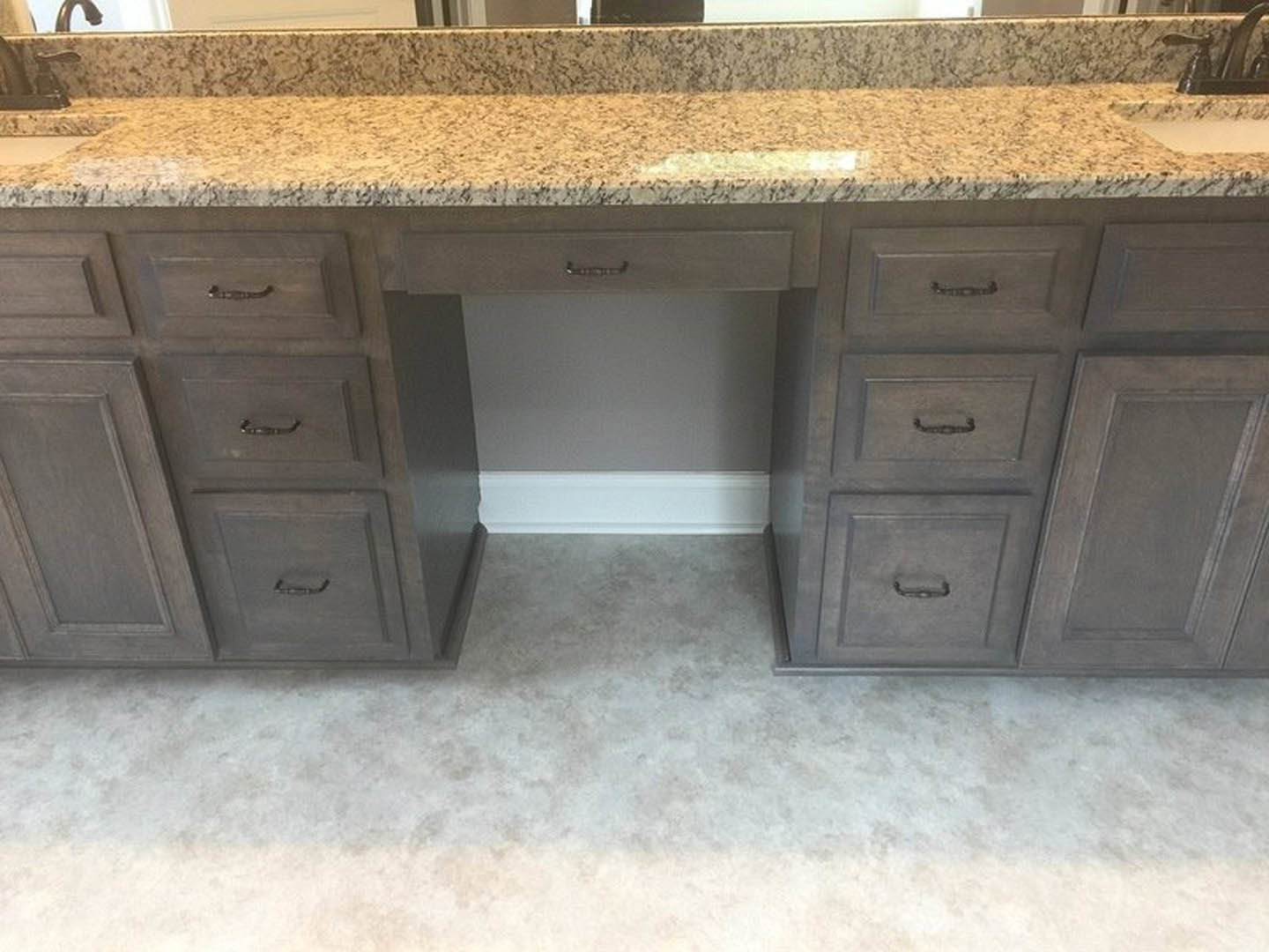 White quartz countertop with light wood drawers, brushed metal handles, grey cabinet door, and light oak flooring
