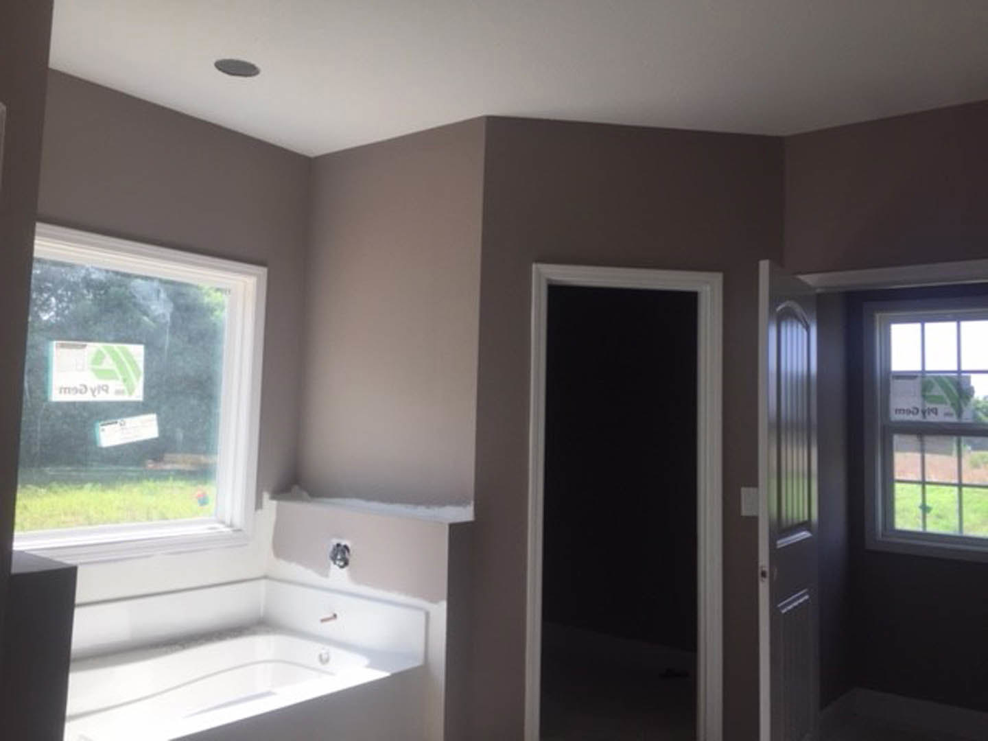 Modern bathroom with freestanding white bathtub, light-colored walls, large window, wooden door, and built-in sink with chrome fixtures