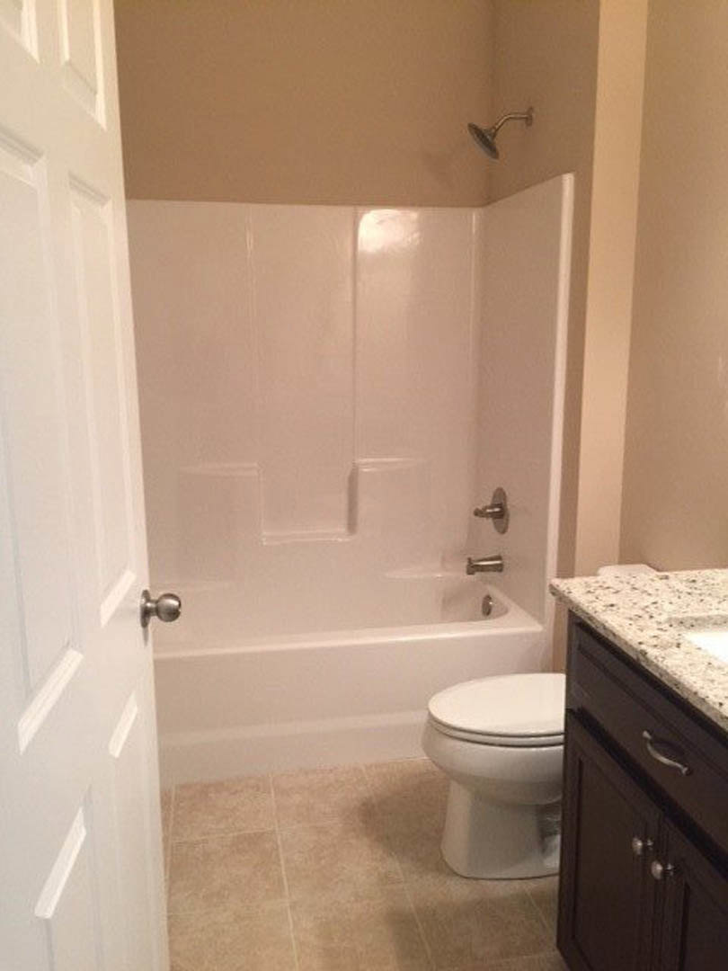 Modern bathroom featuring white tile walls, glass-enclosed shower, and sleek toilet with chrome fixtures