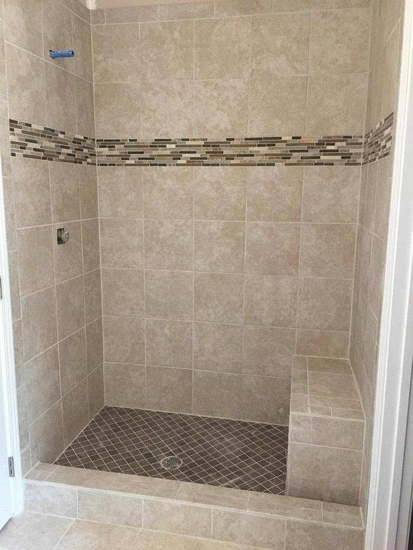 Walk-in shower with marble tile floor, linear drain, and white tiled wall