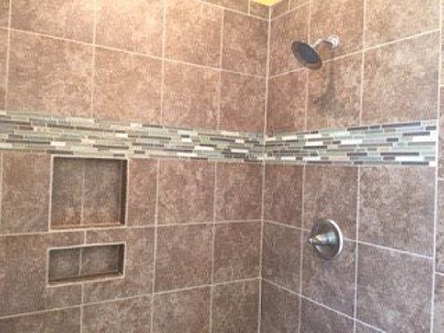 Walk-in shower with large wall-mounted shower head, white subway tile walls, and light gray tile flooring