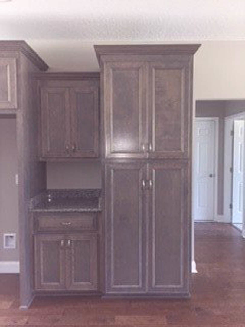 White shaker kitchen cabinets with black hardware, hardwood flooring, and a blurred framed picture on the wall