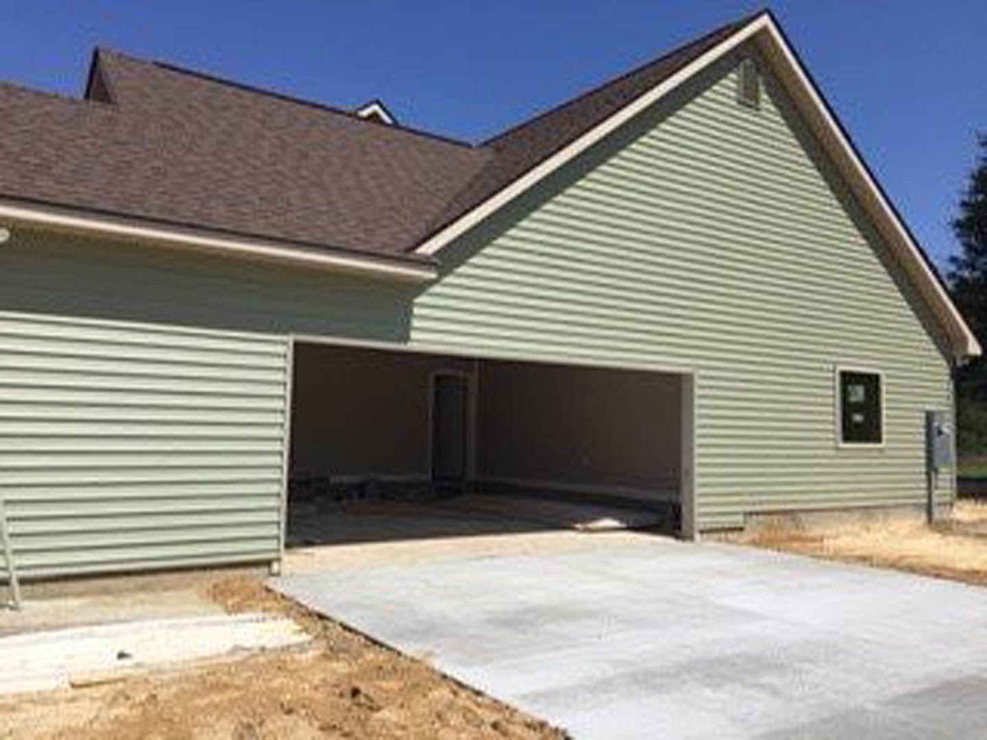 Two-story home with gray siding, white trim, attached two-car garage, asphalt driveway, and large front windows under a gabled roof