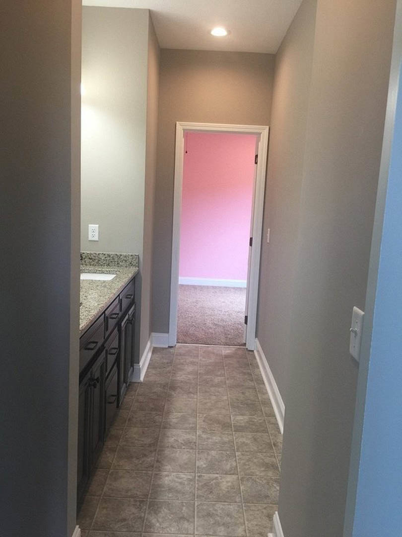 Hallway with pink plaster wall, white door frame, and tile flooring