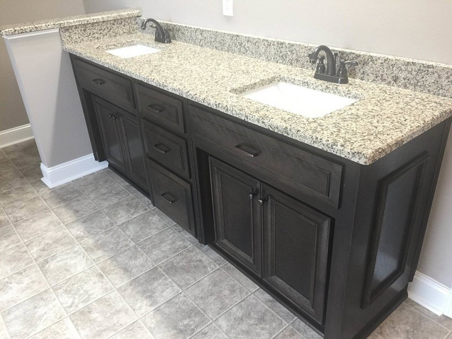 Granite bathroom countertop with undermount sink, chrome faucet, white cabinetry, and tiled backsplash