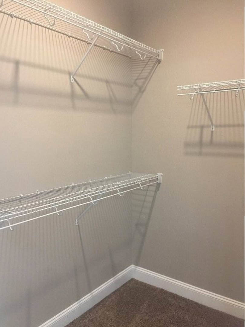Walk-in closet with white wire shelving, carpeted floor, and smooth white plaster walls