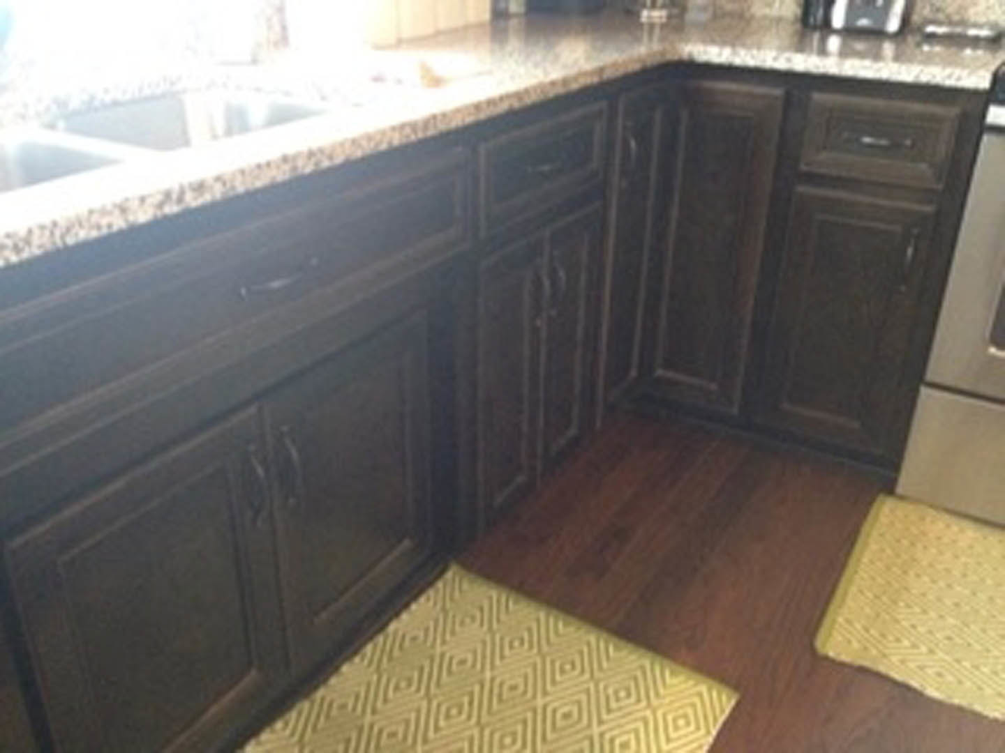 Marble countertop kitchen with white tile backsplash, wood cabinetry, stainless steel sink, and light-colored flooring