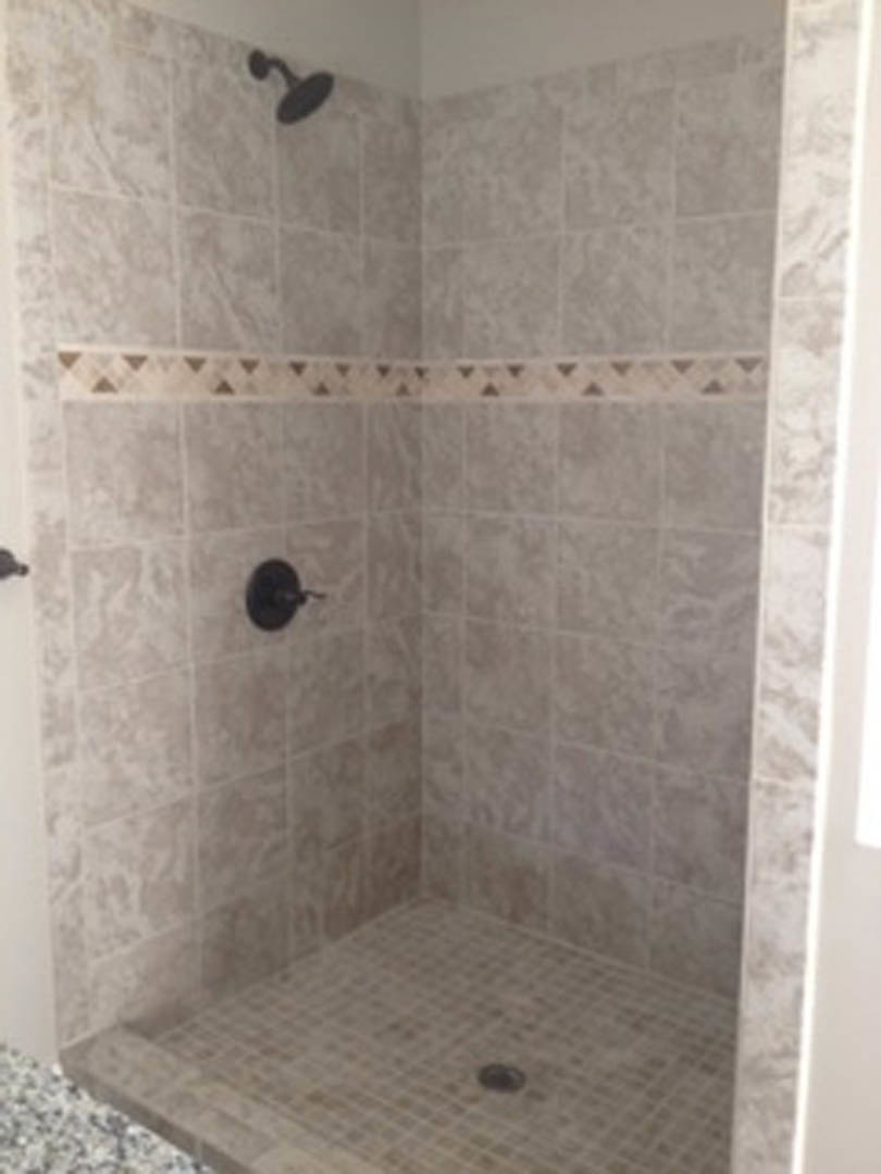 Walk-in shower with large marble tile walls, glass enclosure, and chrome plumbing fixtures