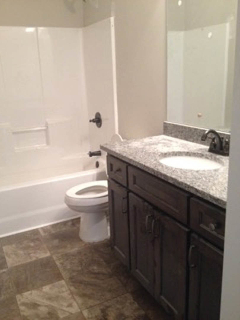 Modern bathroom with white porcelain sink and toilet, light-colored countertop, chrome faucet, and neutral wall tiles