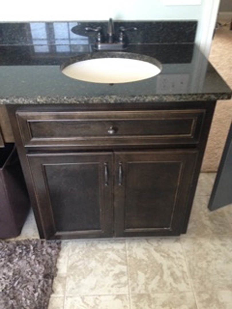 White porcelain sink set in a marble countertop with light wood cabinetry, chrome faucet, and tiled backsplash in a modern bathroom.