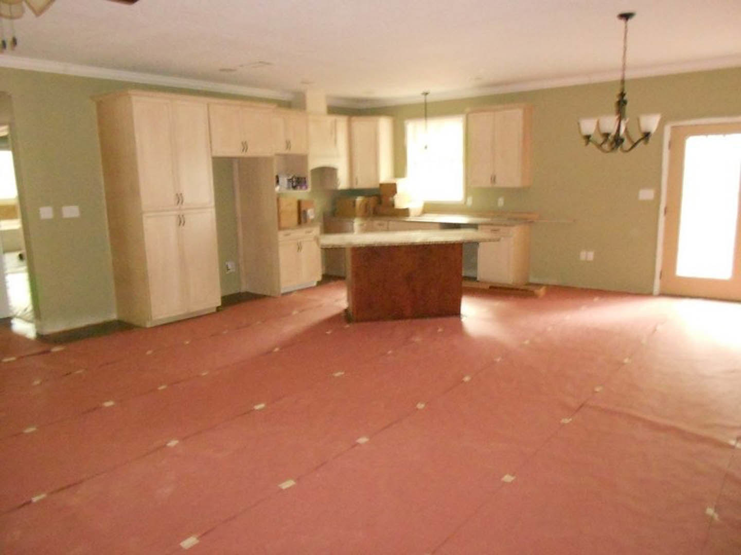 Kitchen with red and white checkered tile floor, wooden table, white cabinetry, stainless steel sink, and overhead lighting fixture