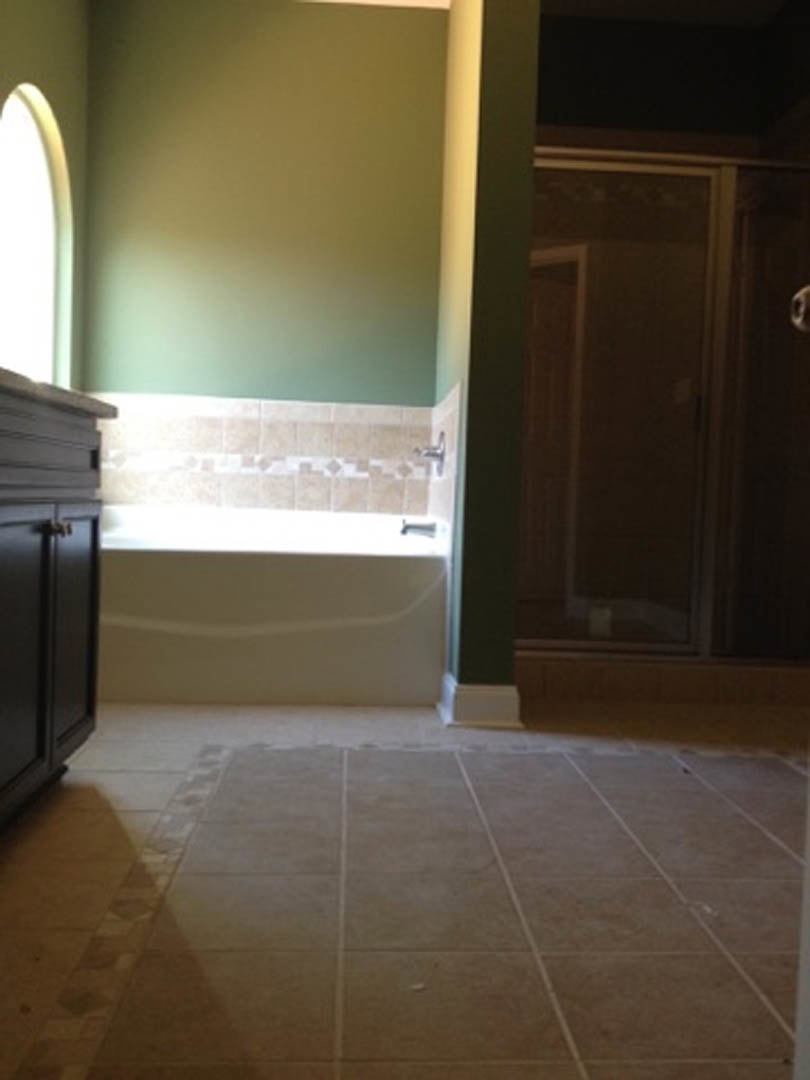 Modern bathroom featuring a freestanding bathtub, glass-enclosed shower, light gray tile flooring, white walls, and dark wood cabinetry with stone countertop