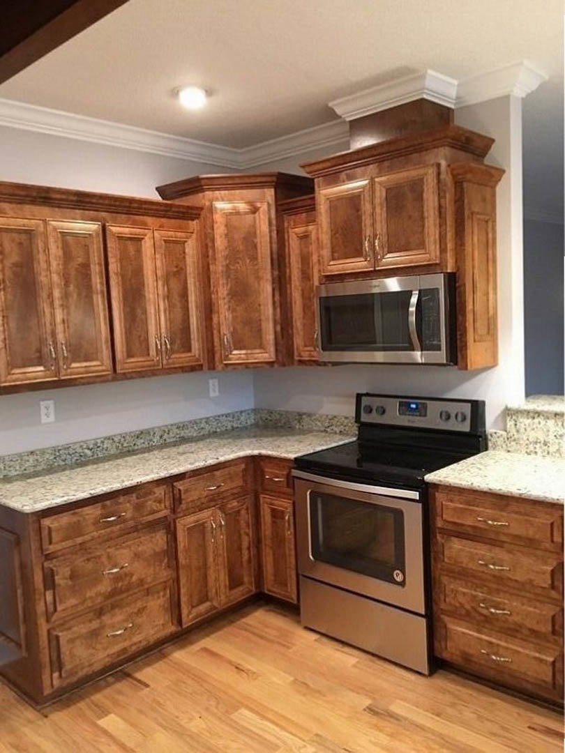 Kitchen featuring wooden cabinets, granite countertops, stainless steel oven with black cooktop, built-in microwave, and hardwood flooring