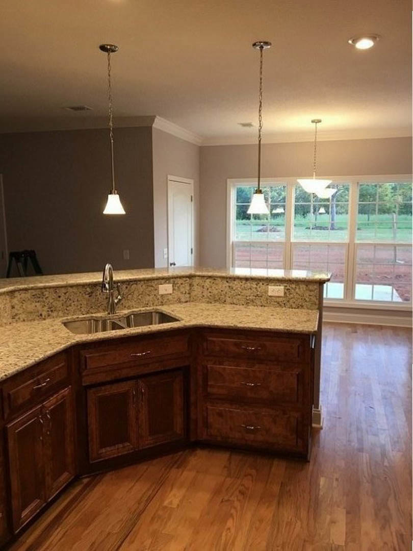 Kitchen with wood flooring, marble countertop, stainless steel sink, white cabinetry, and tiled backsplash