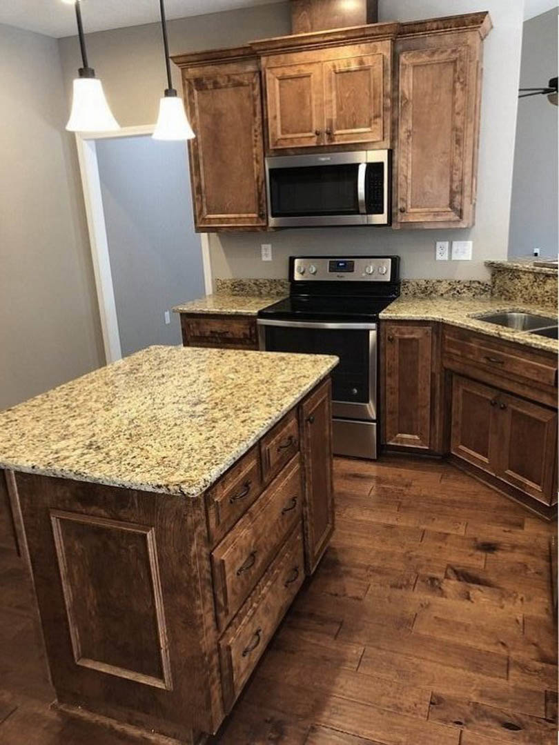 Granite countertops, stainless steel stove and oven, white cabinetry, microwave above cabinets, kitchen island with marble top and drawers, hardwood flooring