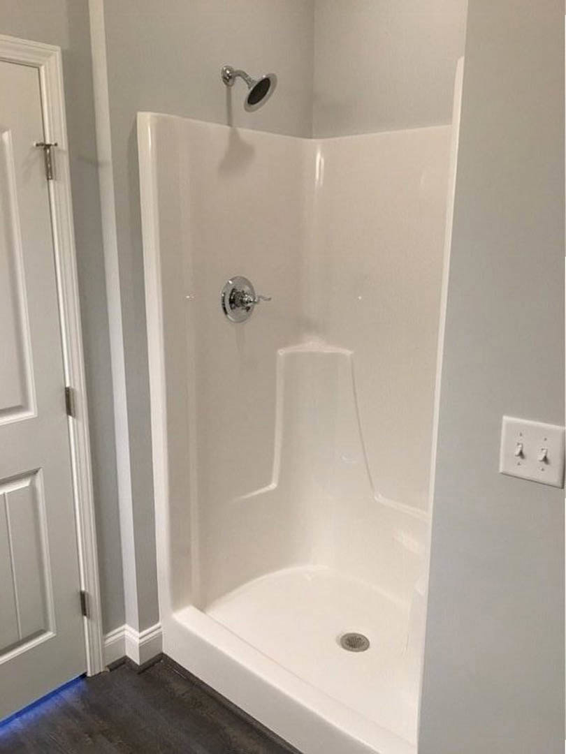 Walk-in shower with glass enclosure, white subway tile walls, chrome fixtures, and built-in niche for toiletries
