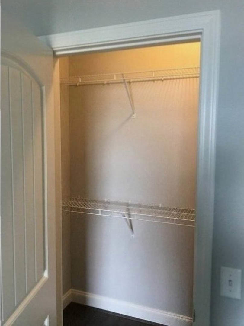 Walk-in closet with built-in white shelves, recessed ceiling lights, and smooth plaster walls