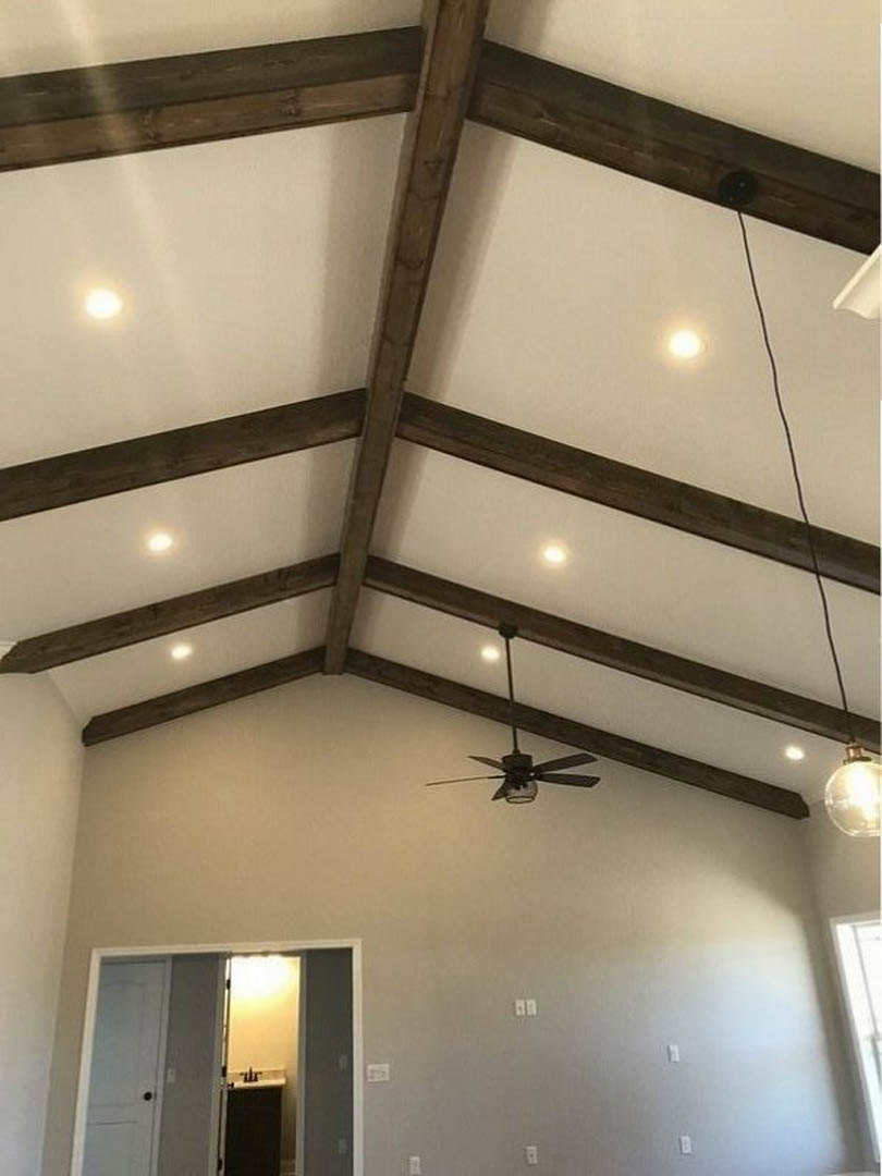 White plaster ceiling with recessed lights and a central ceiling fan, open door leading to bathroom, visible wall and interior finishes.