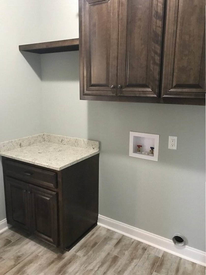 Kitchen with granite countertop, white cabinetry, small wall pass-through, wood flooring, black baseboard, and visible electrical outlet