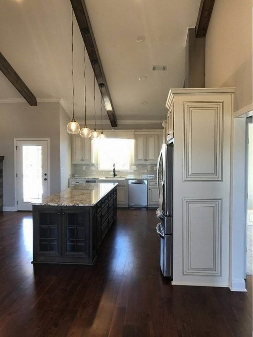Marble kitchen island with waterfall edge, stainless steel refrigerator, white cabinetry, light wood flooring, recessed lighting, and neutral walls
